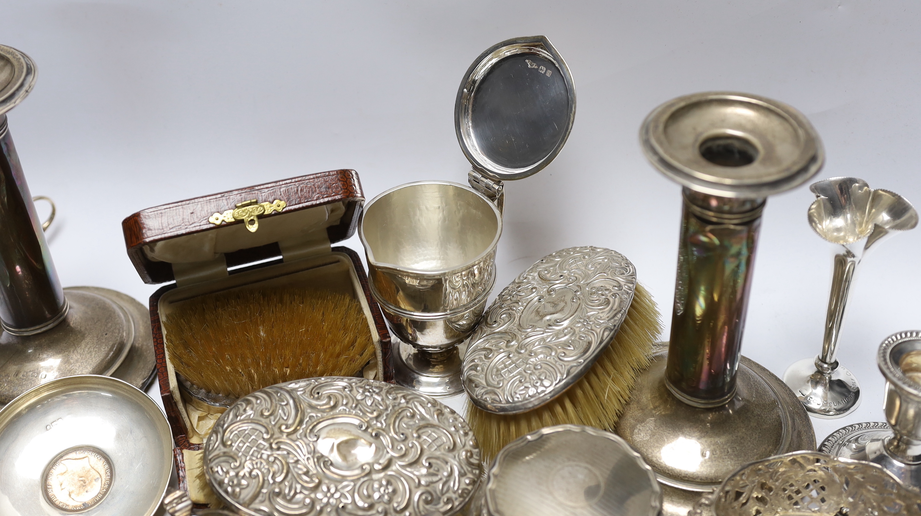 Sundry silver items including a pair of candlesticks, marks rubbed, handled magnifying glass, lidded vase, hand mirror, five brushes, cigarette box, trinket box, toilet jar and eleven other items including a novelty shoe